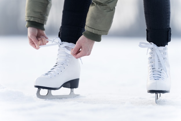 Schnüren der Schnürsenkel von Winterschlittschuhen auf einem zugefrorenen See beim Schlittschuhlaufen