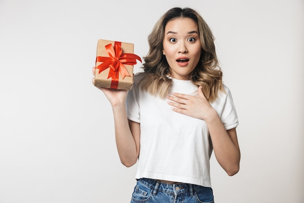 Schockiert emotionale süße junge Frau posiert isoliert über weißer Wand mit Geschenkbox