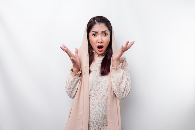 Schockierte asiatische Muslimin mit Kopftuch und weit geöffnetem Mund isoliert durch weißen Hintergrund
