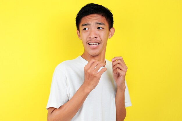 Schockiertes Gesicht des asiatischen Mannes im weißen Hemd auf gelbem Hintergrund.