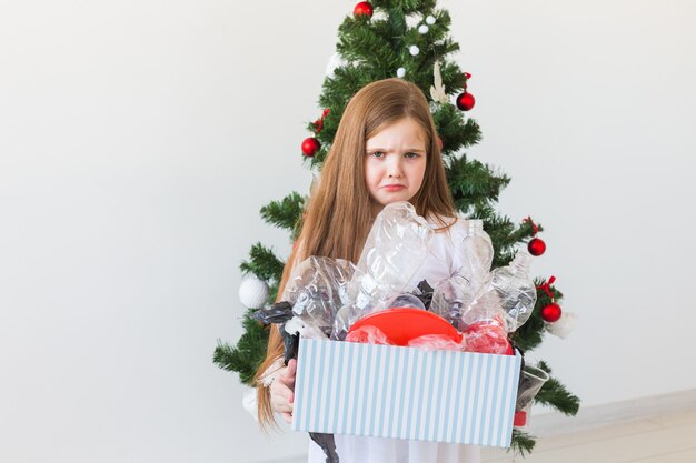 Schockiertes Kind schaut mit geöffneten Augen und besorgtem Gesichtsausdruck Box mit Müll