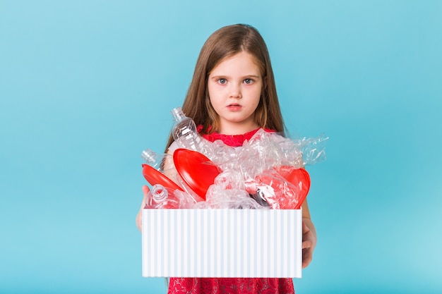 Schockiertes kleines Kind Mädchen schaut mit geöffneten Augen und besorgtem Ausdruck, Box mit verschiedenen haltend