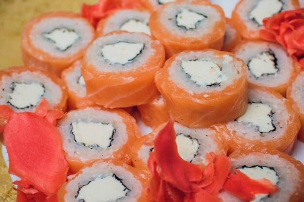 Schön dekoriertes Sushi auf einem Teller und Essstäbchen sind in der Nähe. Sushi ist das traditionelle asiatische und japanische Essen. Sushirolle aus rohem Fisch und speziellem Reis. Diät gesundes Essen.