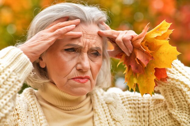 Schöne ältere Frau, die draußen im Herbst aufwirft