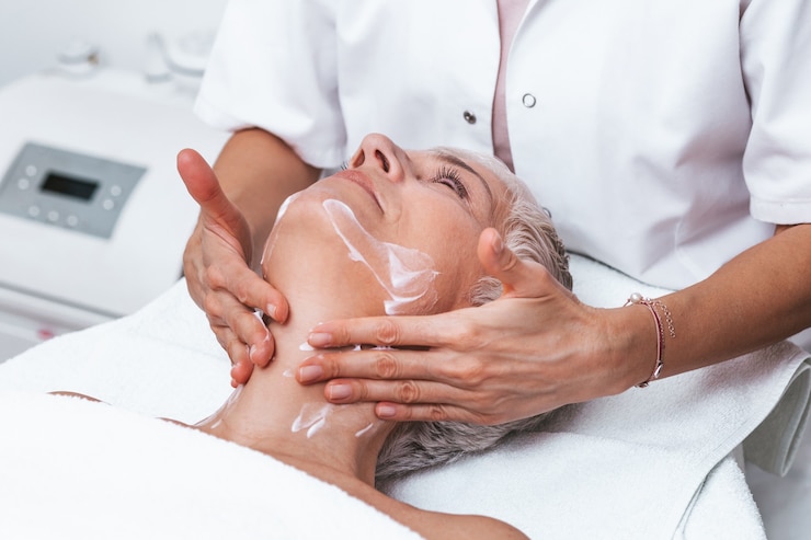 Foto schöne ältere frau, die spa-massage-behandlung im beauty-spa-salon bekommt. schönheitsbehandlung im gesicht.
