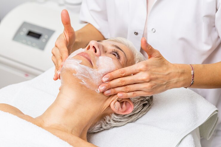 Foto schöne ältere frau, die spa-massage-behandlung im beauty-spa-salon bekommt. schönheitsbehandlung im gesicht.
