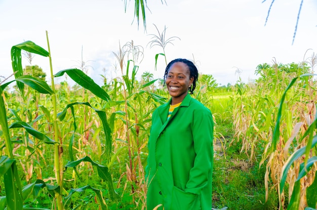 Schöne afrikanische Bäuerin, die sich aufgeregt fühlt, als sie auf der Farm lächelt