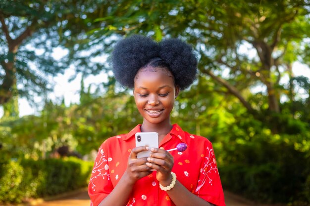 Schöne afrikanische Dame lächelt über das, was sie auf ihrem Smartphone gesehen hat