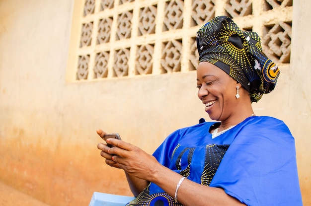 Schöne afrikanische Frau, die sich aufgeregt fühlt, wenn sie ihr Mobiltelefon bedient