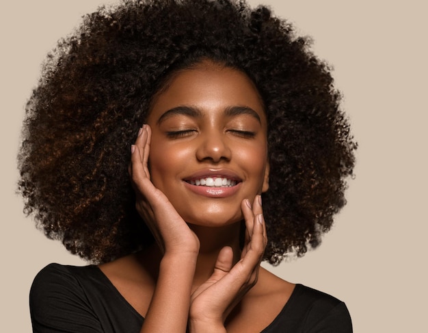 Schöne afrikanische Frau schwarzes T-Shirt Porträt Afro-Haarschnitt, der ihr Gesicht berührt Farbhintergrund braun