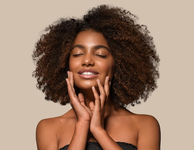Schöne afrikanische Frau schwarzes T-Shirt Porträt Afro-Haarschnitt, der ihr Gesicht berührt Farbhintergrund braun
