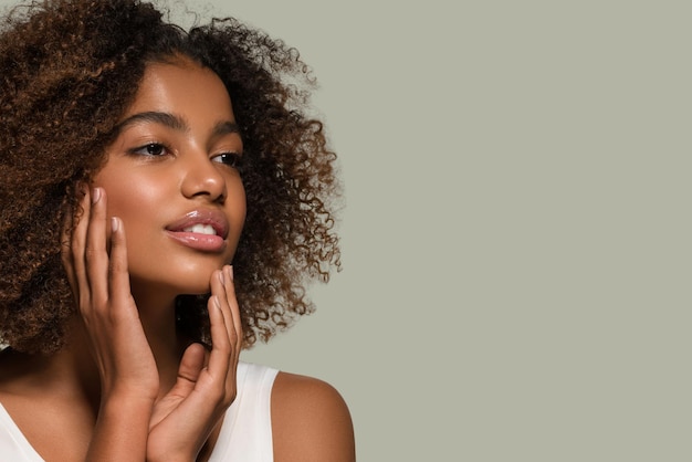 Schöne afrikanische Frau weißes T-Shirt Porträt Afro-Haarschnitt, der ihr Gesicht berührt Farbhintergrund grün