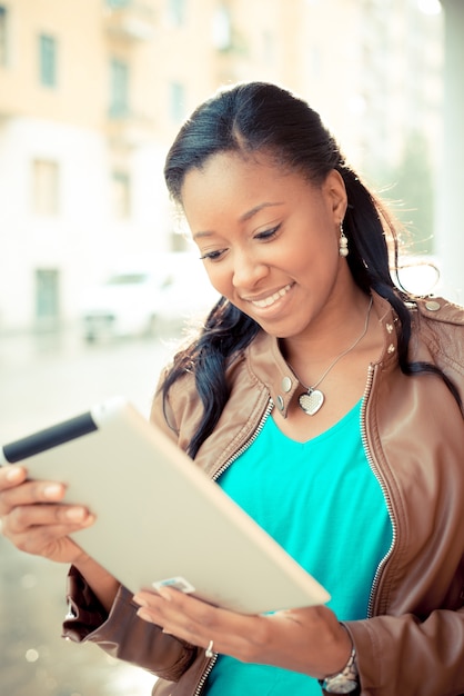 schöne afrikanische junge Frau, die Tablette verwendet