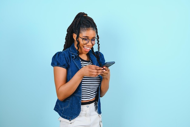 Schöne Afro-Frau, die mit dem Handy spricht und auf blauem Hintergrund lächelt