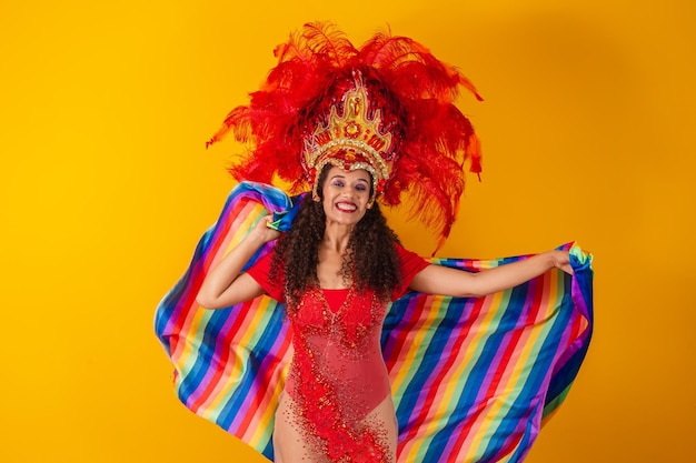 Schöne Afro-Frau in LGBT-Flaggen-Karnevals-Outfit auf gelbem Hintergrund.