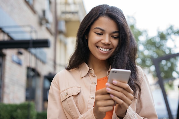 Schöne Afroamerikanerin, die mobile App für Online-Shopping verwendet