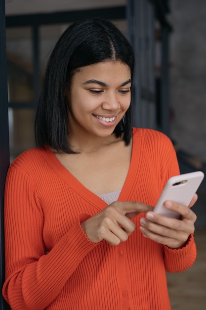 Schöne Afroamerikanerin, die Smartphone-SMS-Kommunikation beim Online-Shopping hält