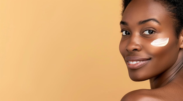 Schöne afroamerikanische Frau legt Feuchtigkeitscreme auf die Wange