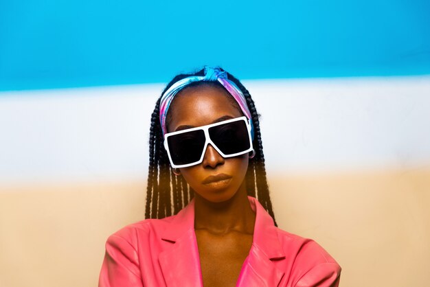 Schöne afroamerikanische Frau mit Afro-Pigtails-Frisur und stilvoller Kleidung - Porträt eines jungen schwarzen Mädchens im Studio