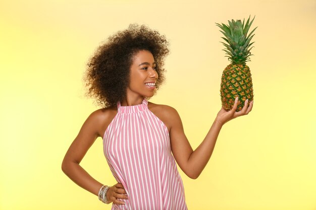 Schöne afroamerikanische Frau mit Ananas auf Gelb