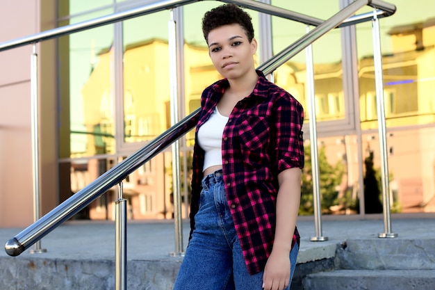 Schöne afroamerikanische Frau mit kurzen Haaren im Sommer auf der Straße.