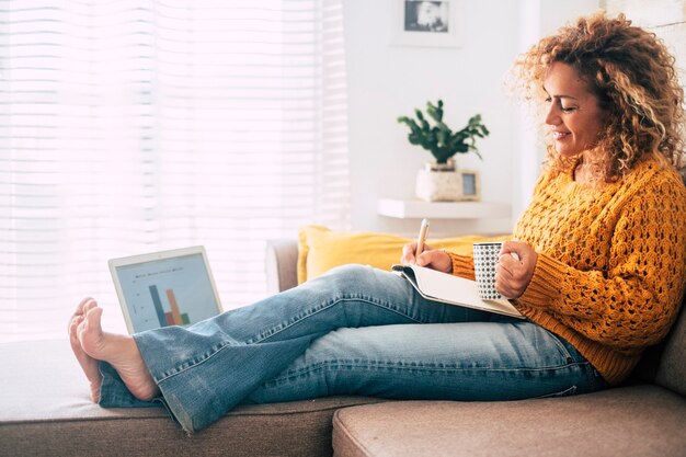 Schöne alleinstehende Frau arbeitet zu Hause mit Papierbuch und Computer-Laptop zusammen im alten und modernen Job-Stil-Konzept