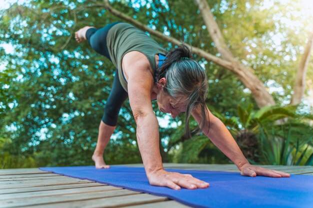 Schöne alte Frau Yoga auf Holzterrasse im Freien in der Natur Gesundheit und Wellness Sport- und Erholungskonzept