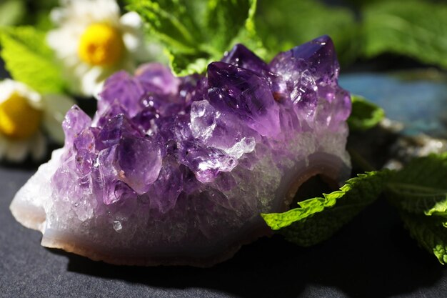 Schöne Amethyst- und Kamilleblumen auf dem Tisch in der Nähe Heilender Kristall