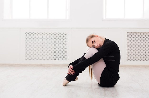 Schöne anmutige Ballerina in Schwarz, die sich im weißen Klassenzimmerhintergrund ausdehnt. Ballettunterricht, Platz kopieren