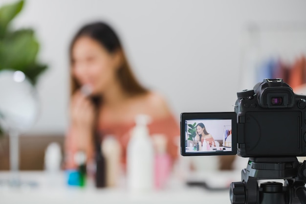 Schöne asiatische Bloggerin zeigt, wie man Kosmetika vor der Kamera schminkt und verwendet und vlog-Video-Live-Streaming zu Hause aufzeichnetHautpflege für ein gesundes Gesichtskonzept