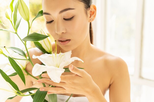 Schöne asiatische Dame mit Blumen im Zimmer