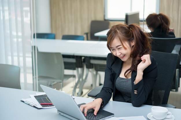 Schöne asiatische Frau, die abends im Büro arbeitet