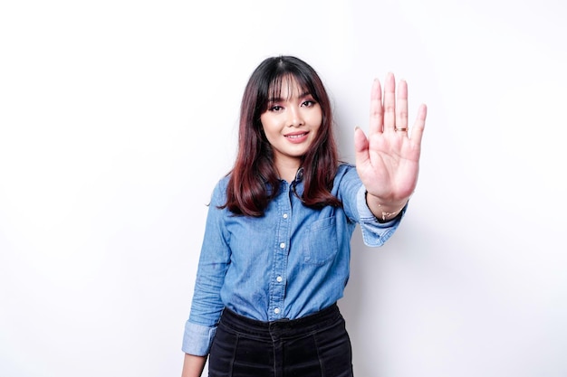 Schöne asiatische Frau, die blaues Hemd mit Handbewegungshaltung des Stopps oder des Verbots mit Kopienraum trägt