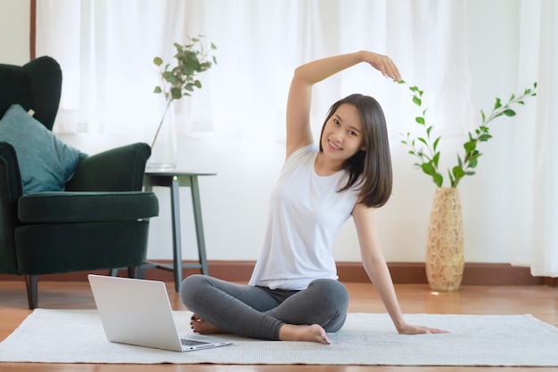 Schöne asiatische Frau, die fit bleibt, indem sie zu Hause für gesunden Trendlebensstil trainiert