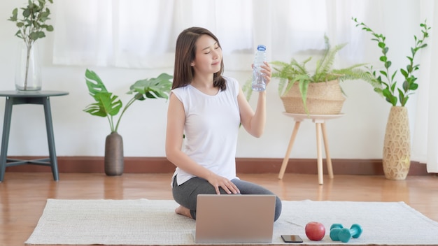 Schöne asiatische Frau, die fit bleibt, indem sie zu Hause für gesunden Trendlebensstil trainiert