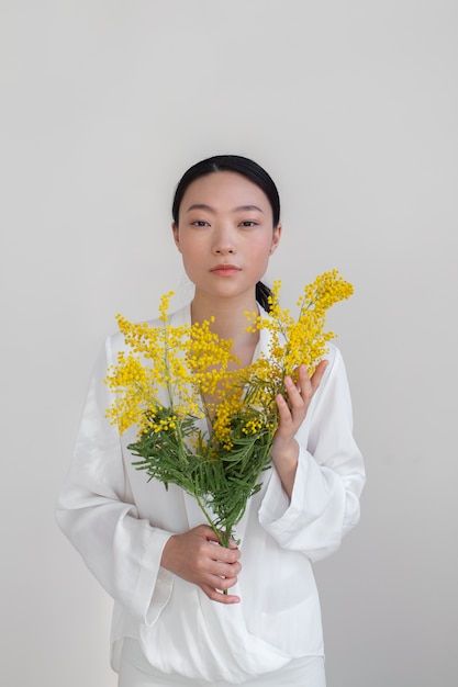 Foto schöne asiatische frau, die gelbe blumen mit perfekter haut hält