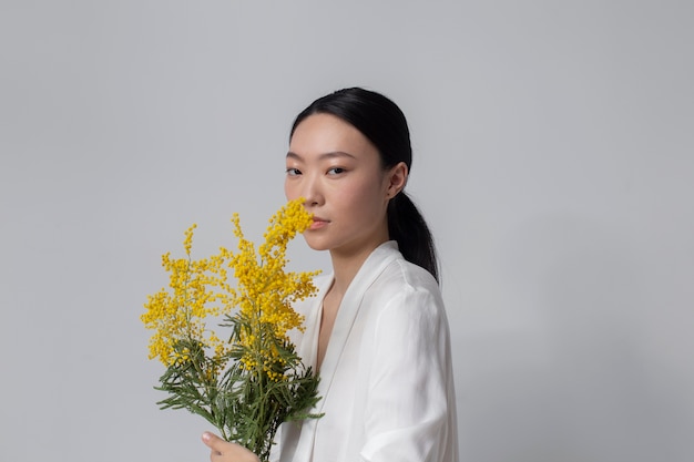 Foto schöne asiatische frau, die gelbe blumen mit perfekter haut hält