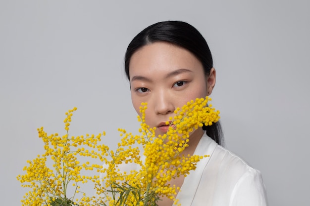 Foto schöne asiatische frau, die gelbe blumen mit perfekter haut hält