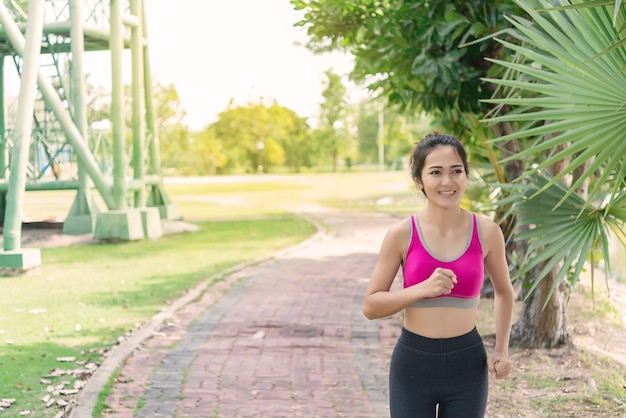 Schöne asiatische Frau, die im Park joggtÜbungsmädchenkonzeptThailand-Menschen gute Gesundheit