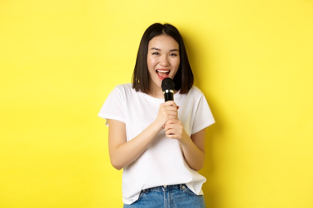 Schöne asiatische Frau, die Karaoke singt, führen mit Mikrofon durch