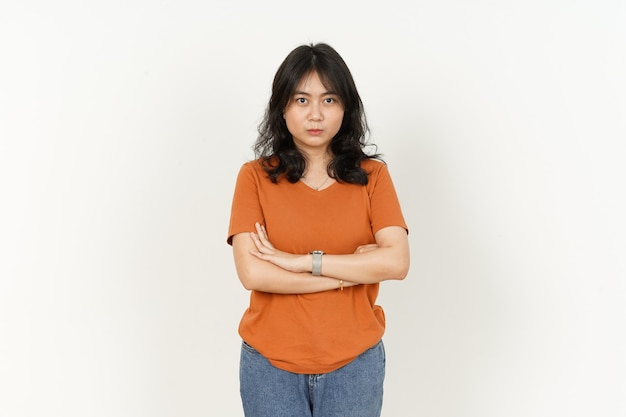 Schöne asiatische Frau, die orangefarbenes TShirt trägt, verschränkte Arme und wütenden Gesichtsausdruck