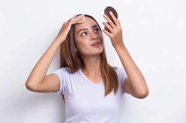 Schöne asiatische Frau, die Puder beim Make-up der Kosmetik auf weißem Hintergrund aufträgt