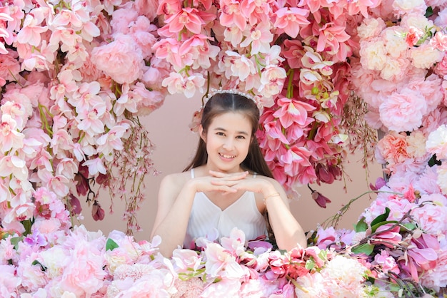 Schöne asiatische Frau, die weißes Kleid sitzt, das mit schöner rosa Blume sitzt.