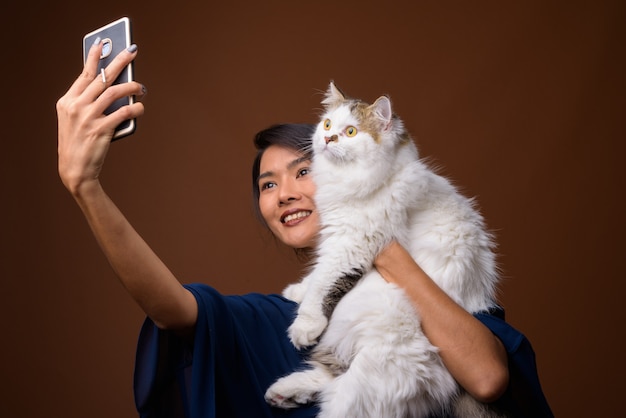 schöne asiatische Frau gegen braune Wand