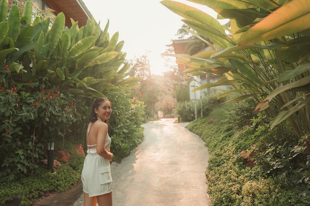 Foto schöne asiatische frau geht und lächelt im garten im resort