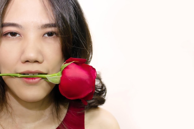 Schöne asiatische Frau hält rote Rose im Mund mit Nahaufnahme am Valentinstag