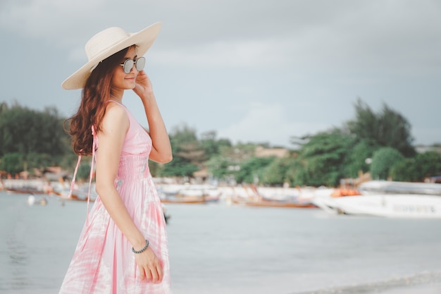 Schöne asiatische Frau im rosa Kleid an einem tropischen Strand Porträt einer glücklichen jungen Frau lächelnd