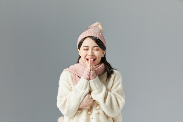 Schöne asiatische Frau in einem weißen Pullover und Hut