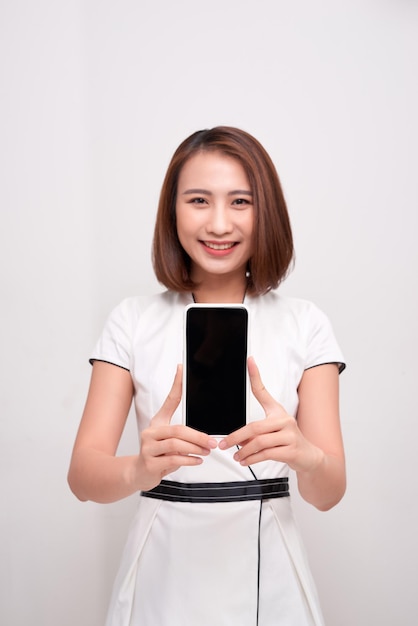 Schöne asiatische Frau mit leerem Bildschirm-Smartphone auf weißem Hintergrund