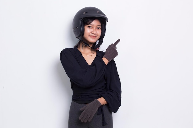 Schöne asiatische Frau mit Motorradhelm, die mit den Fingern in verschiedene Richtungen zeigt